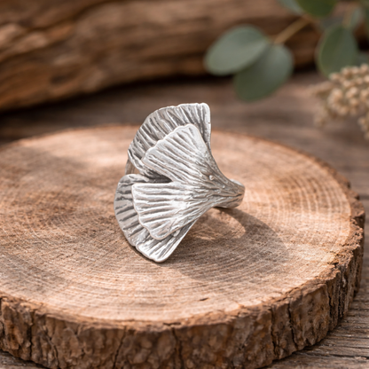 silberring in Form eines Ginkgoblattes auf einer Holzscheibe